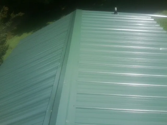 New green metal panels meeting at the ridge of a roof — Flat Roof Repair work by our crew in Mountain View